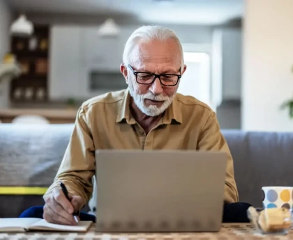 Homme souriant devant son ordinateur finalisant sa demande de retraite en ligne.