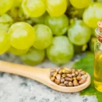 Bouteille d'huile de pépins de raisin avec cuillère en bois et grappes de raisin