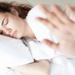 Traversin blanc posé sur un lit avec personne dormant confortablement sur le côté