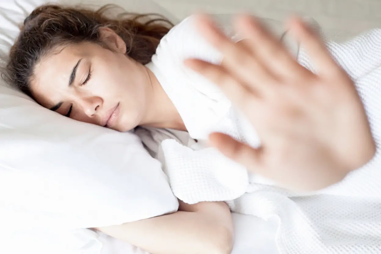 Traversin blanc posé sur un lit avec personne dormant confortablement sur le côté