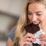 Carrés de chocolat noir sur une assiette avec des amandes, symbolisant le meilleur moment pour en consommer