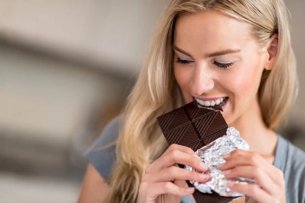 Carrés de chocolat noir sur une assiette avec des amandes, symbolisant le meilleur moment pour en consommer