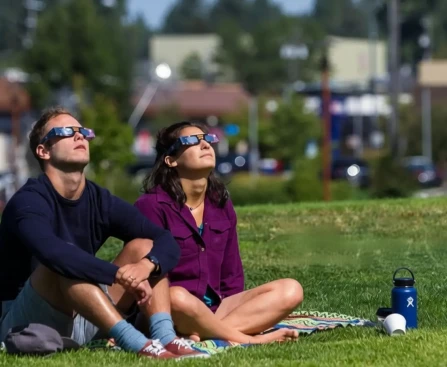 Famille observant ensemble l'éclipse solaire 2026 dans un jardin avec lunettes de protection