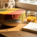 film alimentaire réutilisable à la cire d'abeille enveloppant un bol en céramique sur plan de travail en bois