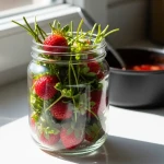 Queues de fraises dans un bocal en verre avec du sirop rouge en arrière-plan