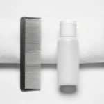Peigne anti-poux à dents métalliques et flacon de lotion anti-poux sur fond blanc épuré